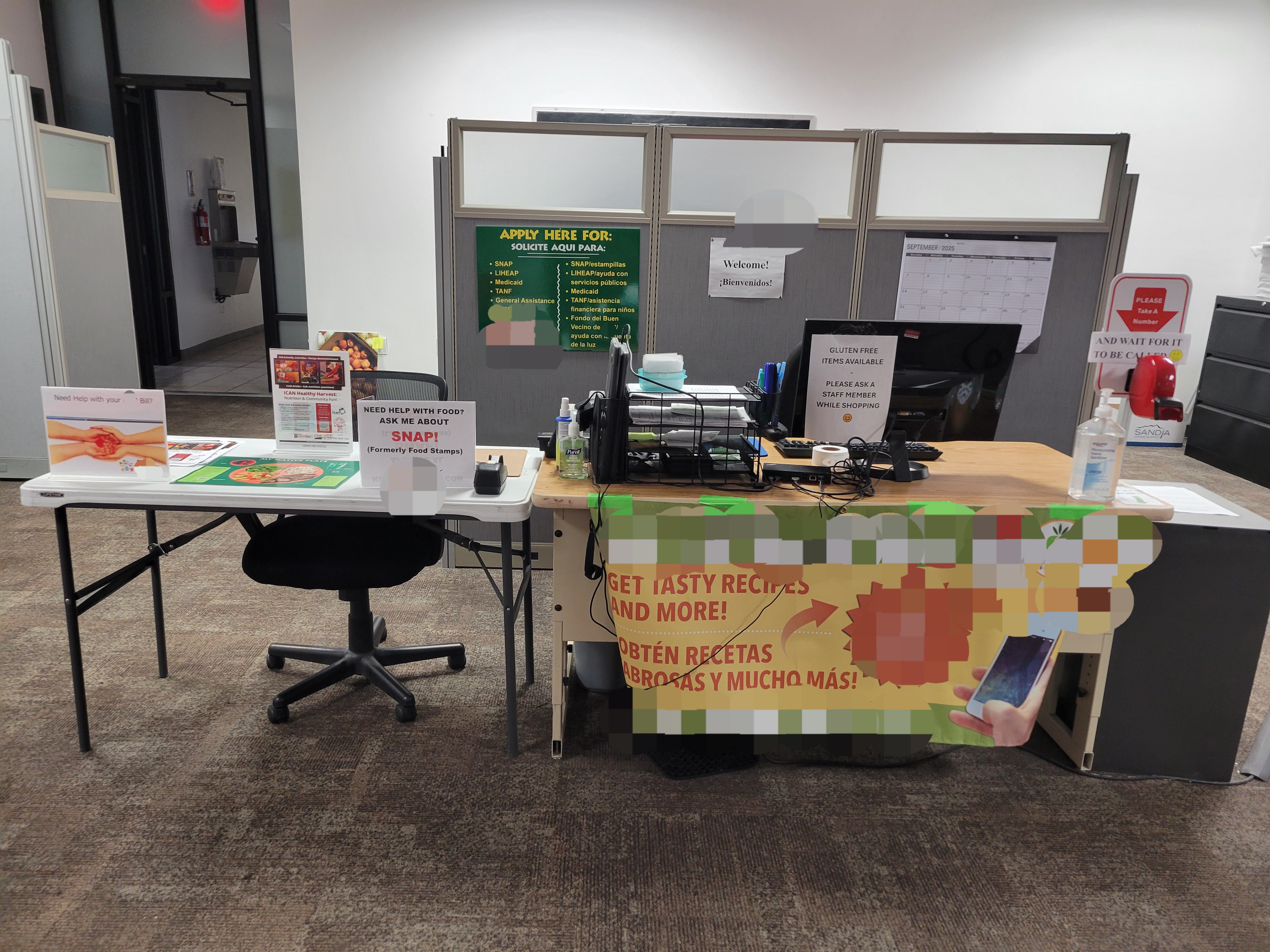 Check in desk with computer and signs listing that they can help you sign up for assistance.